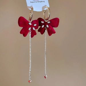 Detail of red velvet bow earrings with marquise stones and long tassel heart drops
