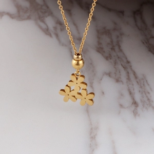 Golden titanium steel necklace with daisy flower pendant on white marble backdrop
