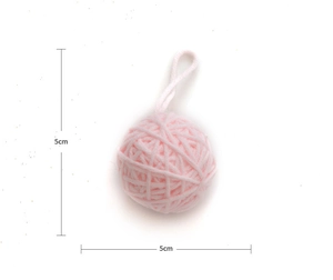 Close-up of a 5cm pink knitted ornament ball with hanging loop for DIY Christmas crafts