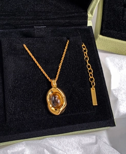 Close-up of gold oval tiger eye necklace in a luxury black velvet gift box