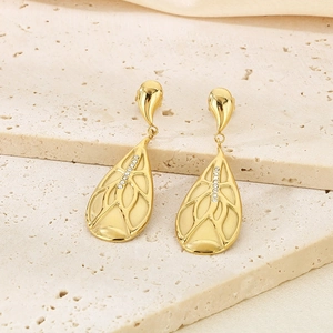 Detailed view of gold drop earrings with textured leaf design and crystal inlay on stone