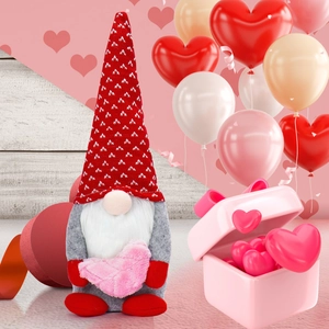 Detail of Valentine gnome plush with red knit hat holding a pink heart ornament
