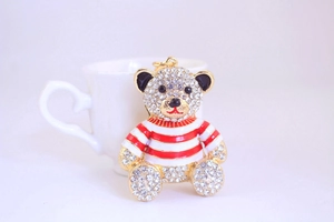 Close-up of a crystal-encrusted bear keychain with red and white striped sweater