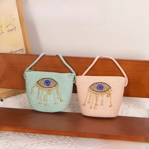 Detail of hand-woven straw bags with crystal devil's eye and fringe tassels for kids