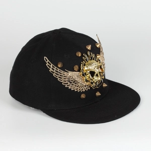 Detail von goldenem Totenkopf und Flügeln mit Nieten auf schwarzer Hip-Hop-Cap
