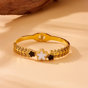 Elegant gold-plated stainless steel cuff with black and white flower charms on beige background
