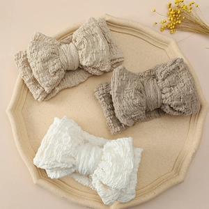 Detailed view of white, beige, and coffee oversized bow headbands on a tray