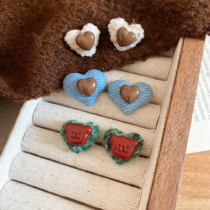 Close-up of resin fabric button heart and bear earrings in blue, white and green