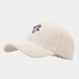 Close-up of three black mushrooms embroidery on beige corduroy baseball cap texture