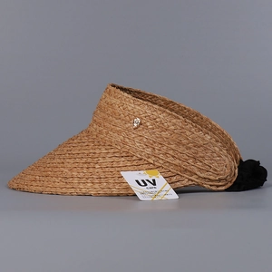 Detail of raffia sun visor featuring a woven texture and elastic band with UV care tag