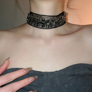 Détail d'un choker en dentelle noire orné de fleurs en strass gris foncé scintillants
