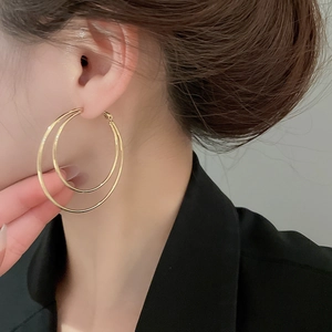 Detailed view of model wearing double-layered polished golden hoop earrings