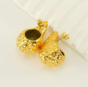 Macro detail of 18K gold teardrop earrings featuring a unique hammered metal texture