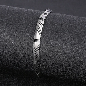 Detailed view of silver titanium steel cuff featuring engraved geometric arrow patterns
