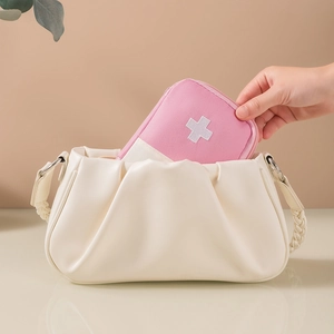 Portable pink medical bag with white cross, showing size by fitting in a handbag