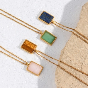 Detailed shot of four vintage rectangular 18K gold plated pendants with colorful gems