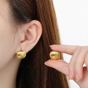 Detailed close-up of golden spherical earrings with vertical striped texture and relief