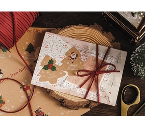 Detail of Christmas gift tags on kraft paper with red velvet ribbon on wooden tray