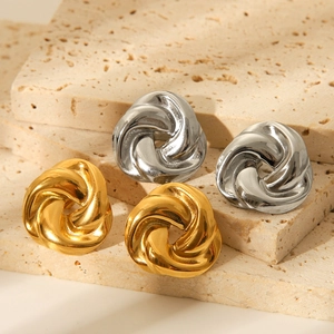 Detail of twisted spiral knot earrings in gold and silver finish on stone base