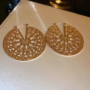 Chic hollow metal disc earrings with intricate geometric patterns and a golden finish