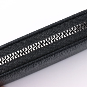 Macro shot of high-quality black pebble leather wallet texture and silver metal zipper teeth