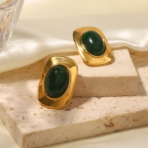 Gros plan de boucles d'oreilles vintage dorées 18k avec pierres ovales vertes