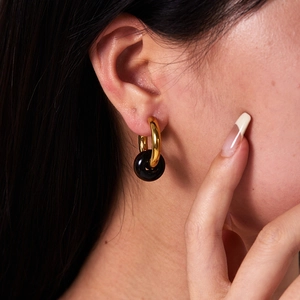 Macro detail of 18K gold-plated earring with vintage texture and black natural stone charm