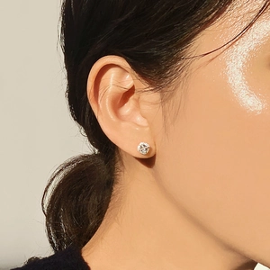 Close-up of square zircon stud earring on ear with silver four-prong setting
