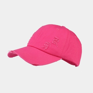 Detail of distressed ripped holes on a vibrant rose pink washed cotton baseball cap