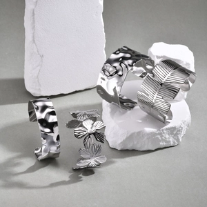 Detailed view of silver stainless steel cuff bracelets with floral and leaf patterns