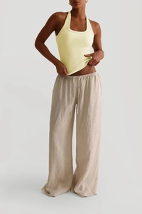 Detail des gelben Neckholder-Tops kombiniert mit beige Leinenhose mit Kordelzug