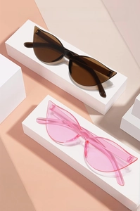 Close-up of trendy cat-eye sunglasses in translucent brown and pink on geometric stands