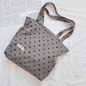 Detail of canvas tote bag with polka dot pattern, bow accents and woven brand label