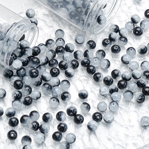 Detailed view of 10mm black and white gradient glass beads spilling from clear tubes
