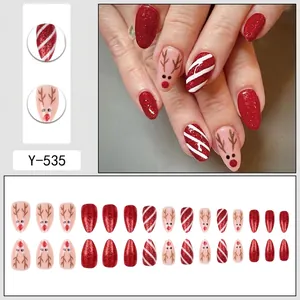Christmas almond press-on nails with red glitter, deer motifs, and candy cane stripes