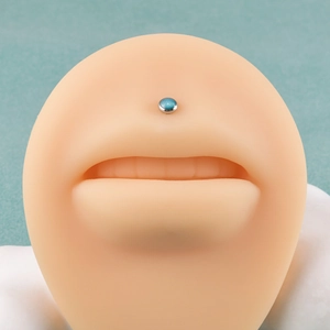 Vista macro del piercing labret in acciaio inossidabile con pietra glitterata blu-verde