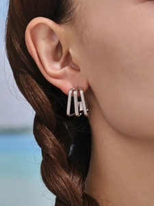 Detailed view of intertwined 18k gold plated multi-layer textured and smooth hoop earrings