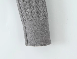 Close-up of grey cable knit cardigan sleeve with ribbed cuff and detailed fiber texture