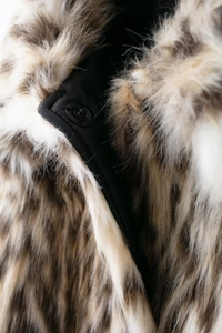 Macro detail of faux fur jacket collar featuring black leather trim and metal snap button