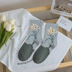 Detail of blue-gray mid-calf socks with white daisy patterns and green toes