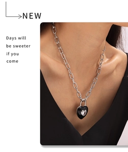 Gros plan d'un collier chaîne en acier titane avec pendentif cœur en émail noir