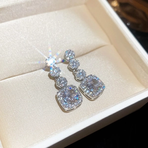 Close-up of sparkling square zircon silver earrings inside a luxury jewelry gift box
