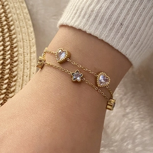 Détail d'un bracelet doré double rang avec pendentifs en zircon en forme de cœur et d'étoile