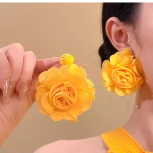 Detailed view of large yellow fabric flower earrings on a model for a summer beach look