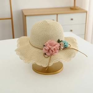 Detail of beige straw hat featuring woven texture with colorful flowers and wavy brim
