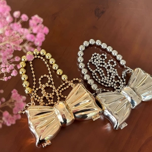 Dettaglio di mini borse a fiocco metallico oro e argento con manici di perle