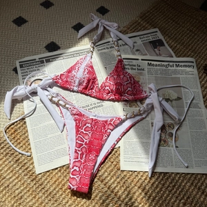 Détail du bikini imprimé serpent rouge et blanc avec chaînes en métal doré chic