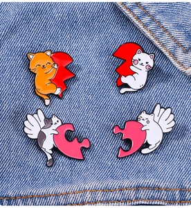 Detail of four colorful cat enamel pins pinned on blue denim fabric accessories