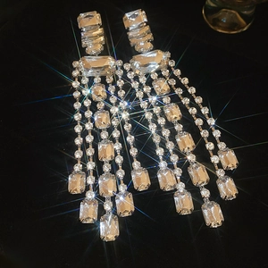 Close-up of sparkling silver tassel earrings with rectangular crystals on black velvet