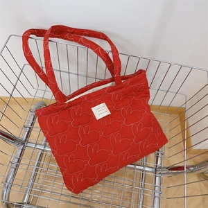 Detail of red quilted shoulder bag with white rabbit embroidery in a metal cart